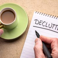 Person writing the word "Declutter" on a notepad