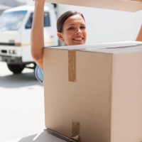 A woman putting a box on top of a stack