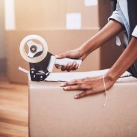 A woman taping up a moving box