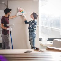 A couple looking at paint swatches by their wall