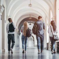 4 college students walking together in a hall