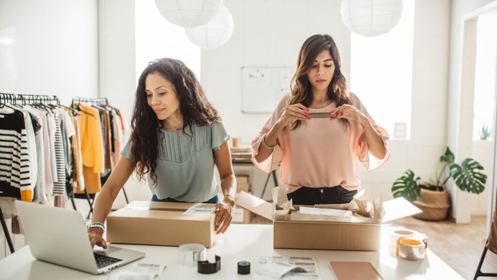 Two small business owners looking at their stock and packing up orders in boxes