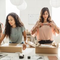 Two small business owners looking at their stock and packing up orders in boxes